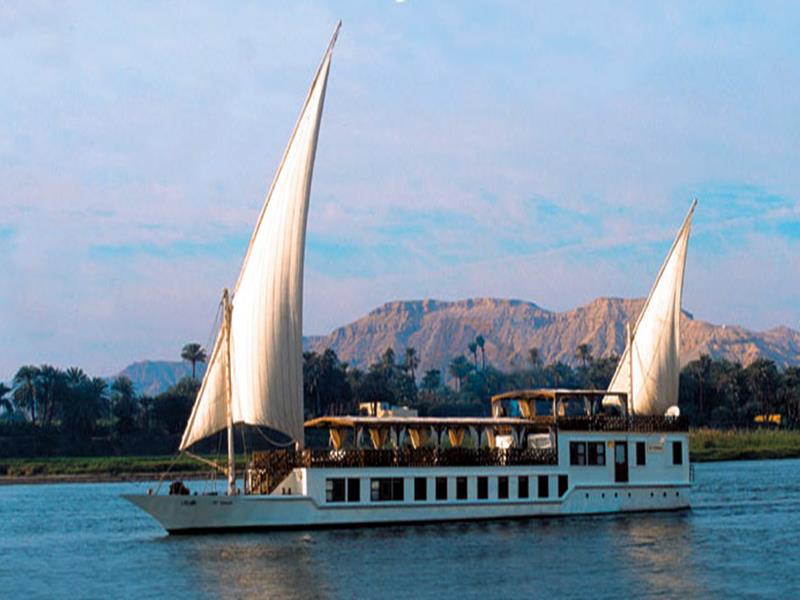 Dahabia unter zwei Segeln auf dem Nil vor Bergkulisse